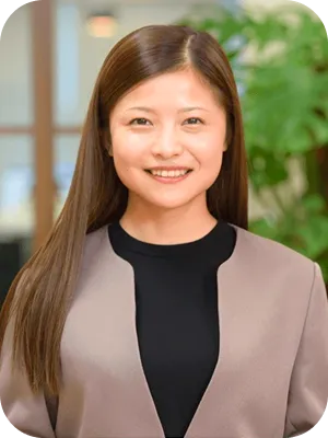 にこやかに微笑む、ジャケットを着用した若い女性スタッフ