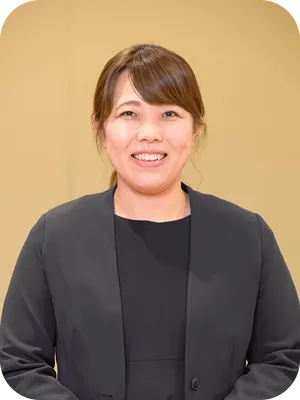 黒いジャケットを着て、親しみやすく微笑む女性スタッフ